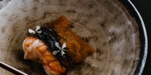 A beautifully plated sushi dish with a traditional Japanese teapot, emphasizing Asian cuisine elegance.