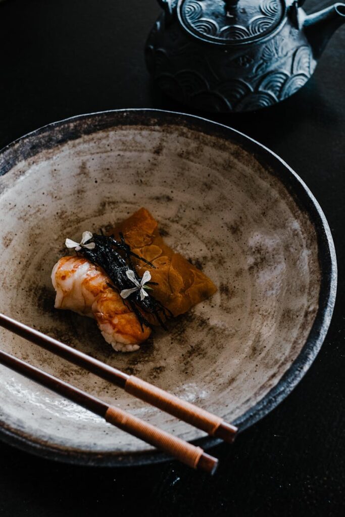 A beautifully plated sushi dish with a traditional Japanese teapot, emphasizing Asian cuisine elegance.