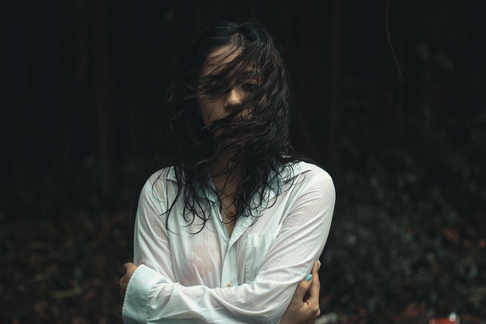 Moody portrait of a woman with wet hair in a forest, expressing solitude and introspection.