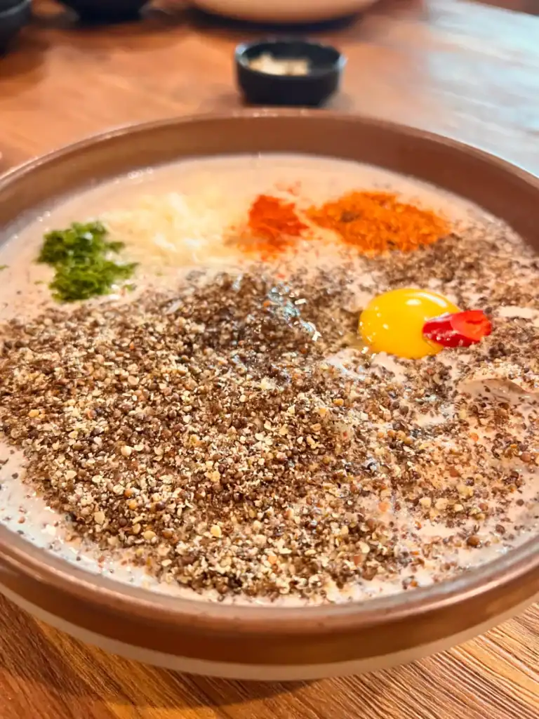 부드러운 계란 노른자와 고소한 견과류 가루, 매운 고추 가루와 신선한 채소가 어우러진 일상 초미세 팁 요리 사진 건강한 식단 추천.